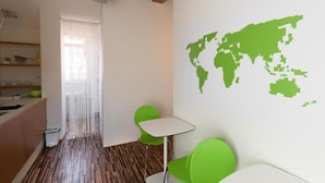 Una habitación con piso de madera, un mapa mural verde, una mesita y una silla verde.