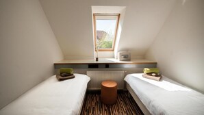 Una habitación pequeña y moderna con dos camas, una ventana y un radiador.