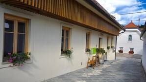 Un edificio con techo inclinado, ventanas grandes y un patio empedrado de piedra.