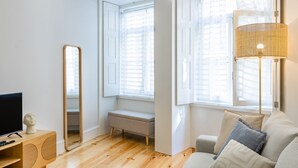 Ein modernes Zimmer mit Holzboden, einer Couch, einer Bank, einem Fernseher und einem großen Spiegel.