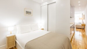 Ein modernes Schlafzimmer mit einem großen Bett, Nachttischen, einem Kleiderschrank und einem gerahmten Bild an der Wand.