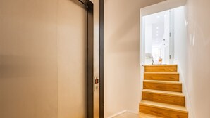 Ein modernes Interieur mit einer Holztreppe, die zu einem hellen Raum führt.