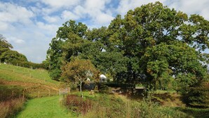 A rural landscape with a path leading to a small house surrounded by trees and grass. - The Wagon House (Launceston)