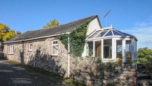 A stone building with a covered porch and a small window. - The Wagon House (Launceston)