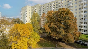 A multi-story residential building with balconies and a pedestrian pathway. - Spacious Apartment | 2 Bedrooms, Balcony, Close to Metro (Warszawa)