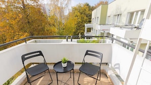 A balcony with two black chairs, a small round table, and a potted plant. - Spacious Apartment | 2 Bedrooms, Balcony, Close to Metro (Warszawa)