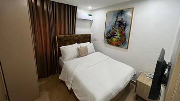 Una habitación de hotel con cama, un cuadro, aire acondicionado y televisión.