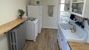 A compact kitchen with a gas stove, white cabinets, a wooden countertop, and a built-in sink. - Downtown Colorado Springs Studio (Colorado Springs)