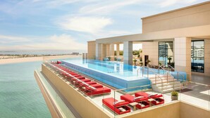 Une piscine sur le toit, avec des chaises longues rouges et une vue sur la plage.