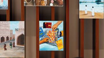 Una pared con varios cuadros enmarcados, incluyendo una pintura de una mujer y un niño, una escena con comida, y una representación de una mano sosteniendo una bandera.