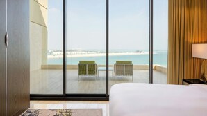 Une chambre d’hôtel dotée d’une grande porte-fenêtre coulissante donnant sur un balcon avec vue sur la plage.