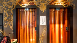 Two elevator doors with a metallic finish and a sign indicating floor numbers. - Moxy Dortmund (Dortmund)