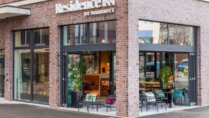 A brick building with large windows and outdoor seating. - Residence Inn by Marriott Dortmund (Dortmund)