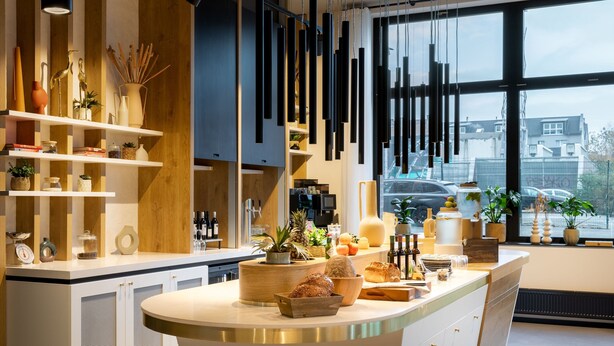 A modern kitchen with a central island, wooden shelves, and hanging pendant lights. - Residence Inn by Marriott Dortmund (Dortmund)