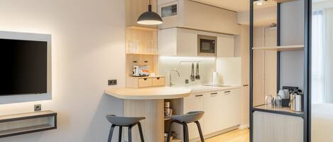 A modern kitchen with a built-in island, bar stools, and a flat-screen TV.