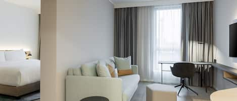 Una habitación de hotel moderna con cama, sofá, escritorio y televisor.