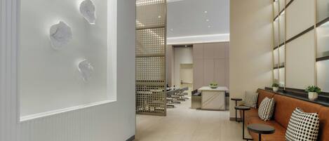 A modern interior with a reception area, a seating area with a sofa and tables, and a decorative wall with geometric patterns.