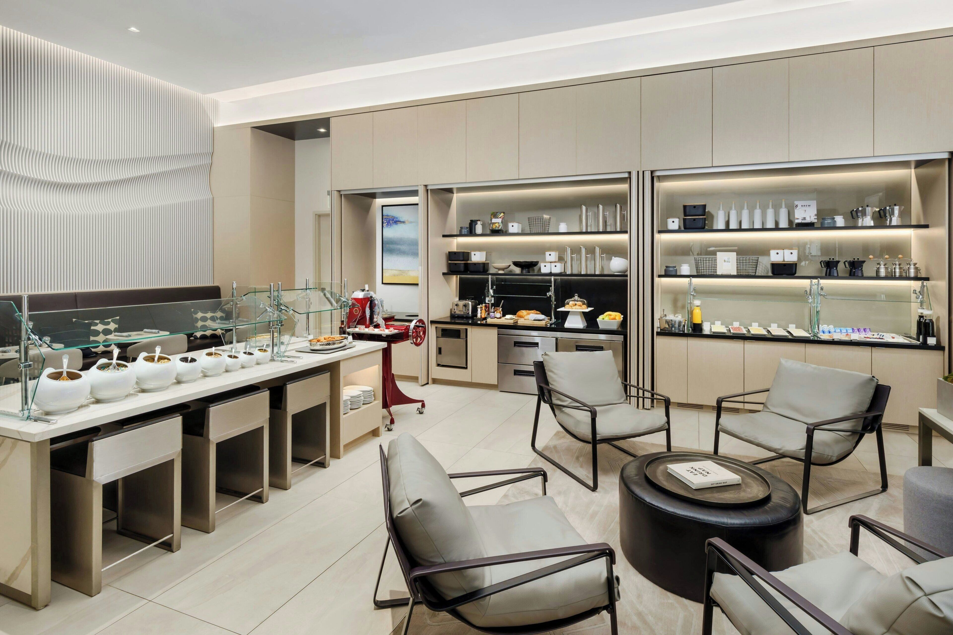A modern kitchen with open shelving, a dining area with chairs, and a bar area with stools.