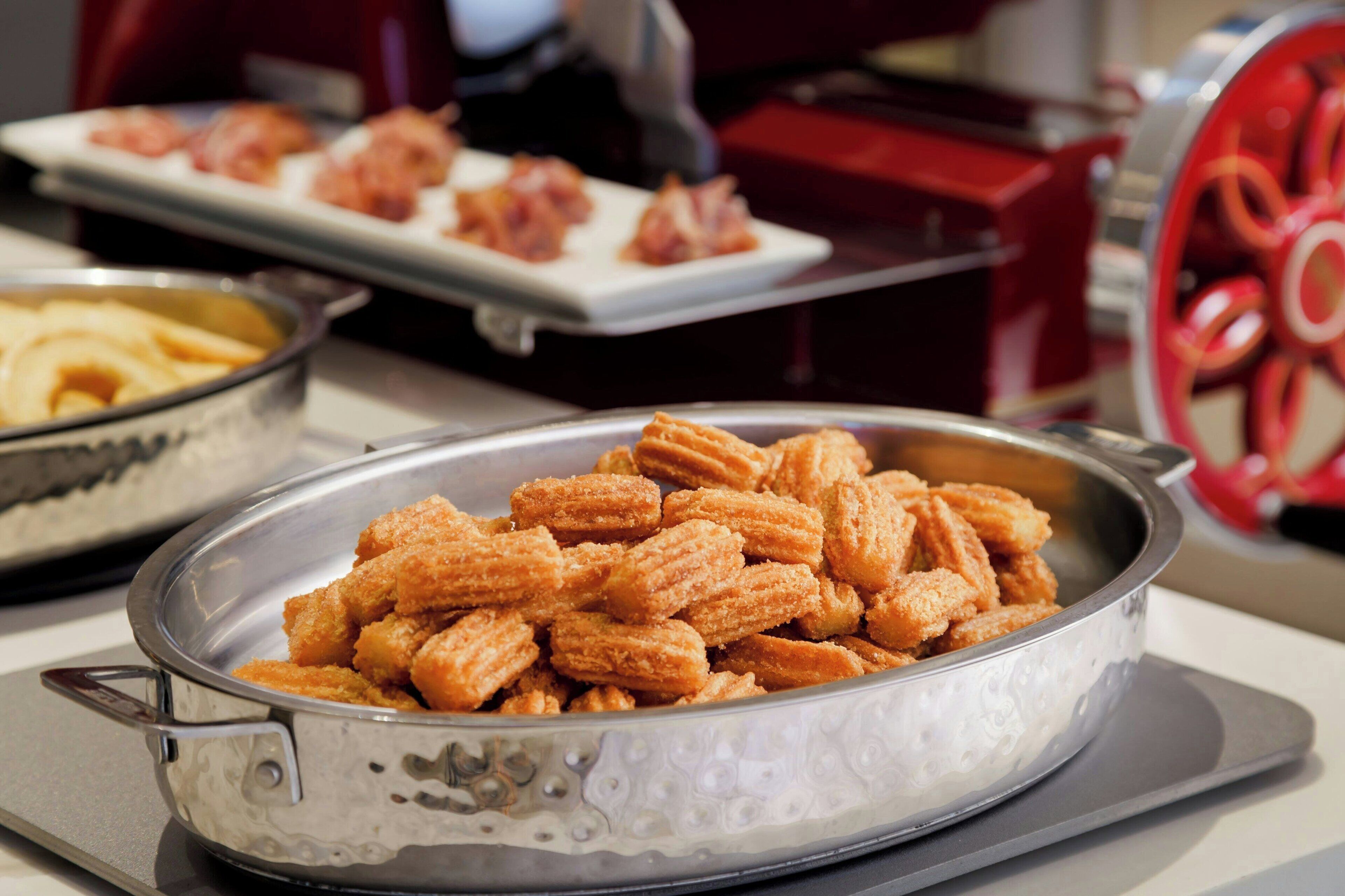 Eine Metalltablett mit einem Serviergeschirr, gefüllt mit Churros.