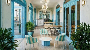 Un vestíbulo de hotel con una zona de estar central, puertas en arco y un candelabro.