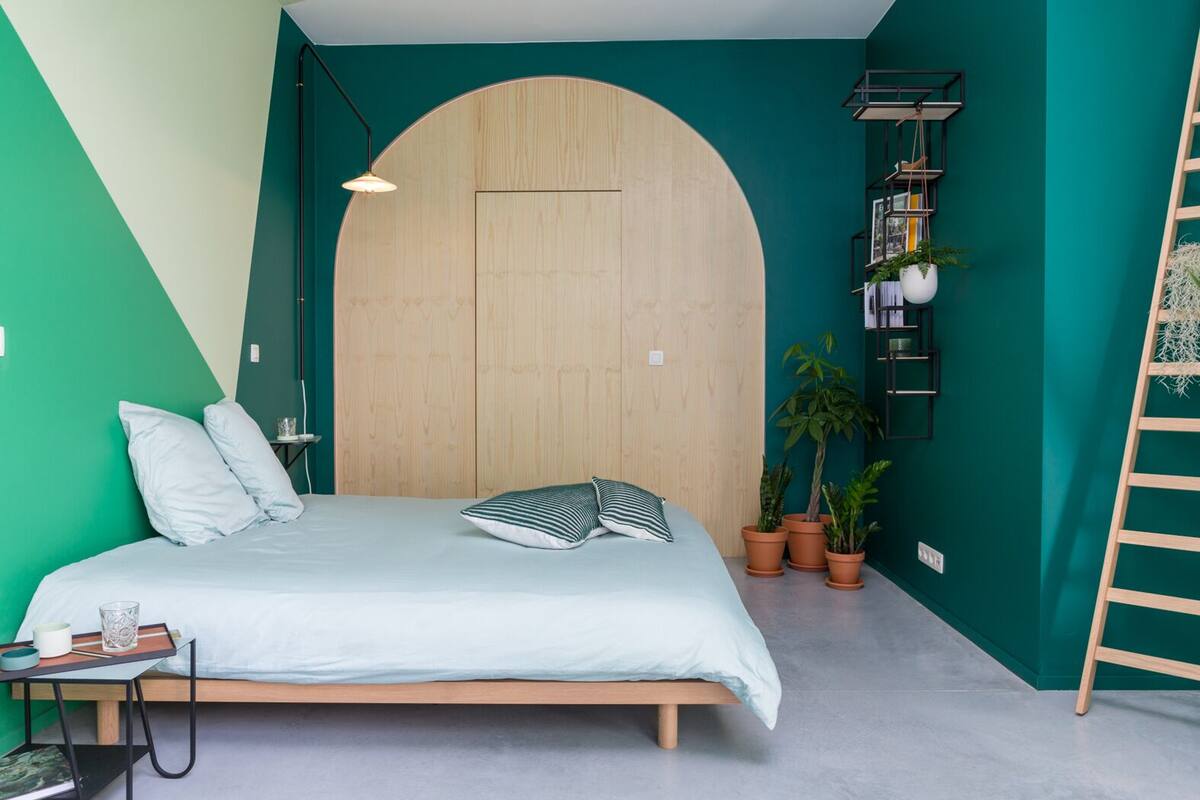 Une chambre à coucher avec un lit, une armoire en bois, une échelle et des plantes en pot.