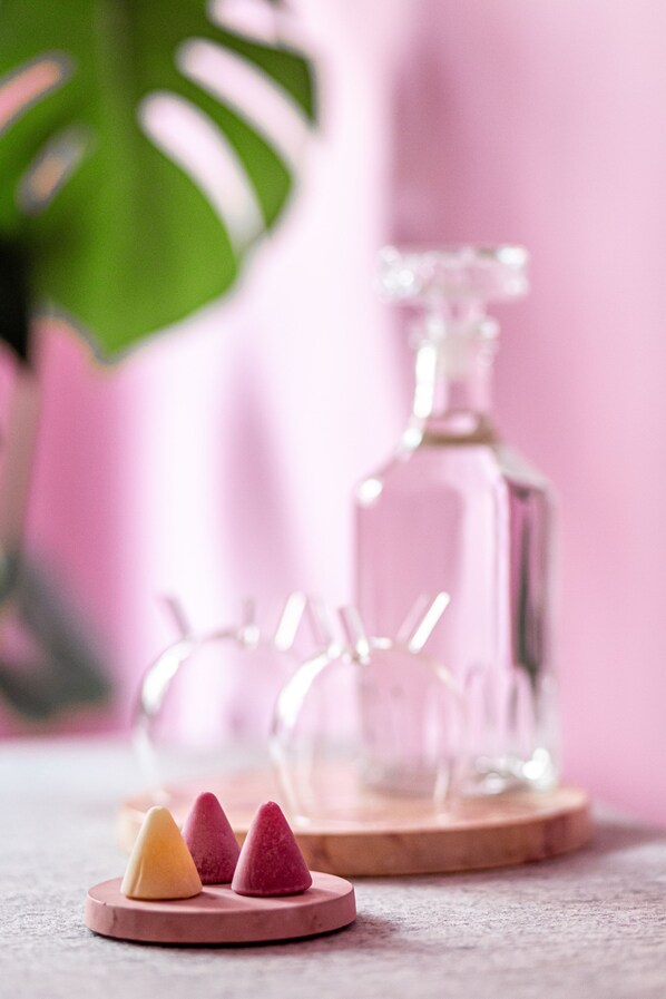 Three conical objects on a round wooden base, a clear glass bottle, and a green plant in the background. - Boutique B&B Graaf. (Ghent)