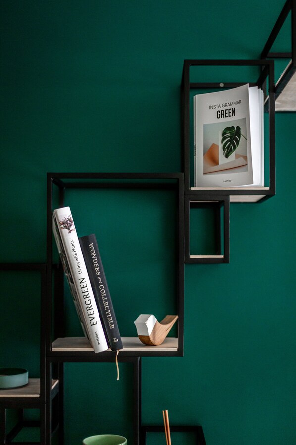 A bookshelf with books and a framed picture against a green wall. - Boutique B&B Graaf. (Ghent)