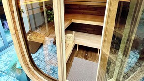 Una estructura de madera con un frente de vidrio curvo, estantes de madera y una pequeña zona de estar.