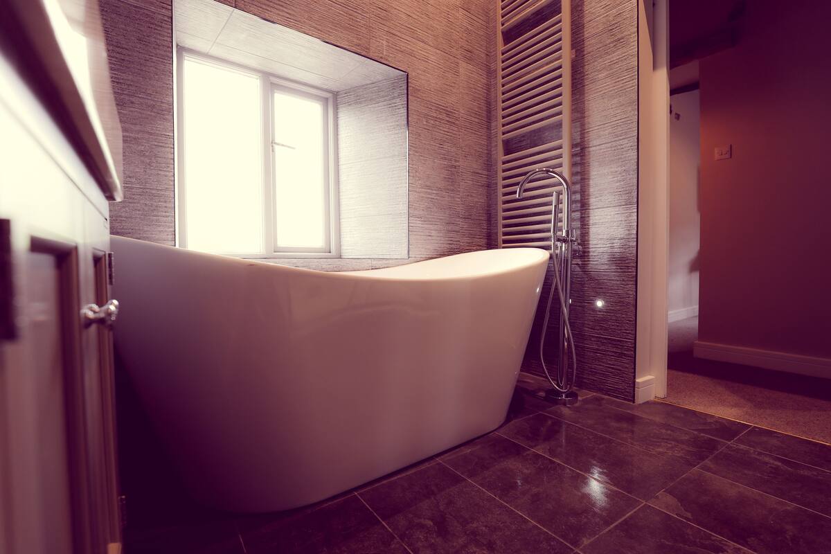A modern bathroom with a freestanding bathtub, a window, and a towel rack.