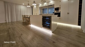 Eine moderne Küche mit Kochinsel, Backofen und Pendelleuchten.