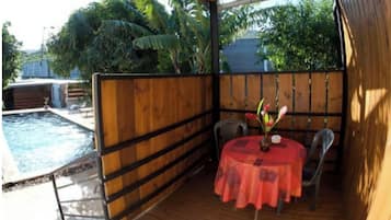 Relax by the pool in a serene, outdoor space with a wooden deck and lush greenery.