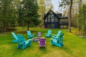 A cabin with a deck surrounded by green chairs and a fire pit. - Muskokan Mirage  Located on Mirage Lake (Novar)