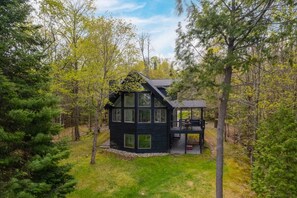A cabin with a deck, surrounded by trees.