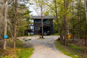 A cabin with a gravel path leading to the entrance, surrounded by trees.