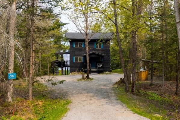 A cabin with a gravel path leading to the entrance, surrounded by trees.