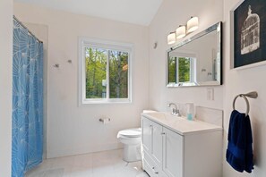 A modern bathroom with a white vanity, a large mirror, and a shower curtain with a geometric pattern.