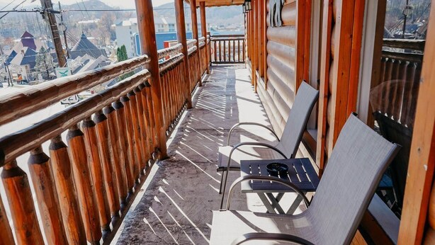 A balcony with wooden railings and two chairs.