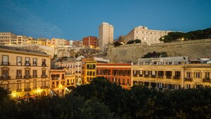 A historic cityscape with a prominent stone tower and a variety of buildings with balconies and windows. - Urban Karalis by Accomodo (Cagliari)