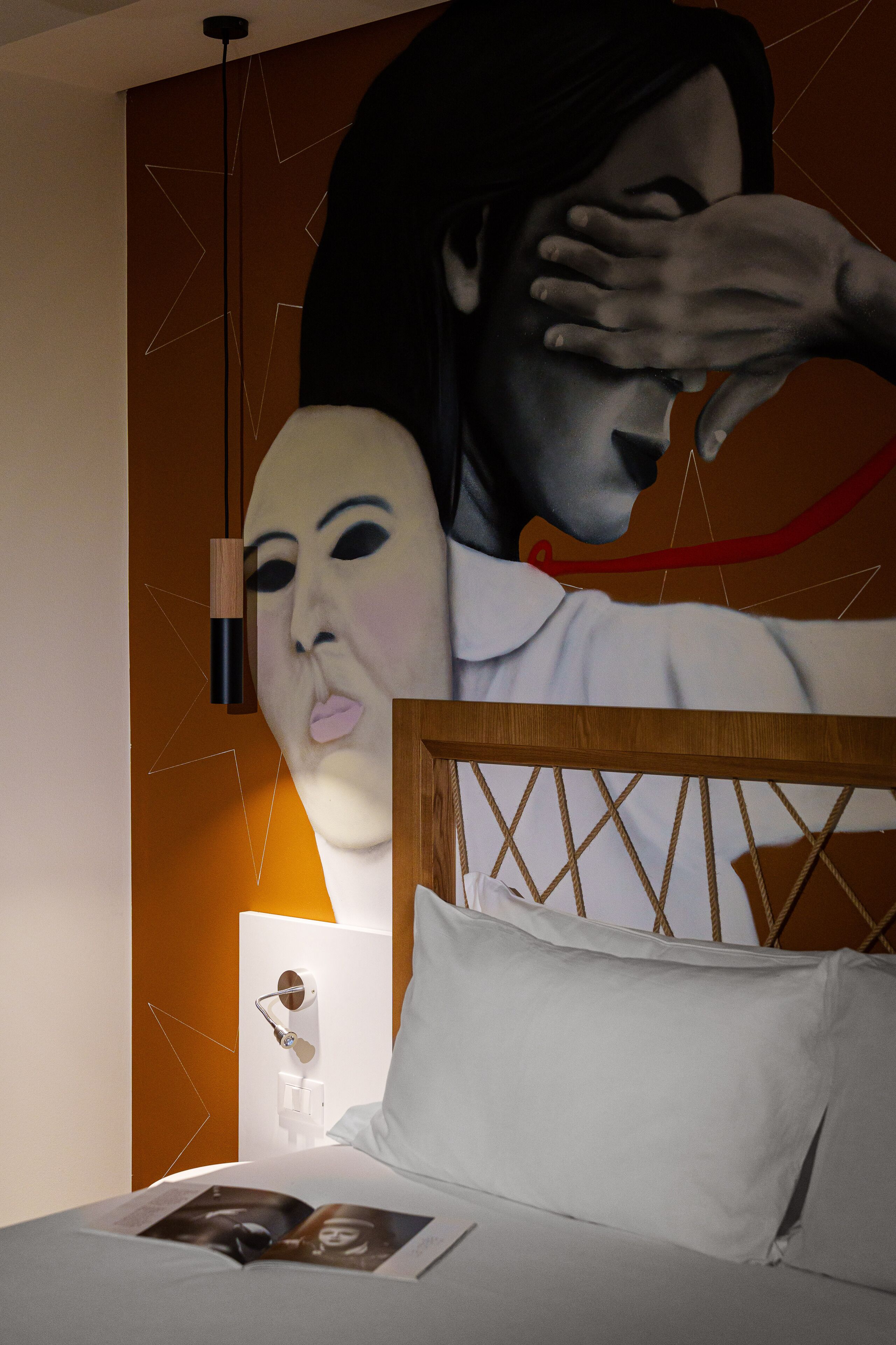 A bedroom with a bed, a nightstand, and a wall-mounted lamp.