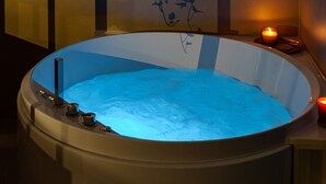 A spa area with a hot tub, a candle, and a vase with flowers. - Urban Karalis by Accomodo (Cagliari)