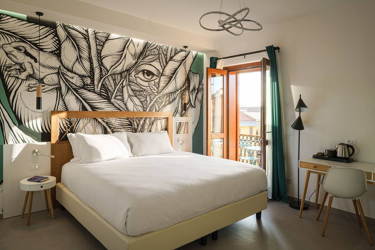 Un dormitorio con una cama grande, un escritorio y vistas al exterior.