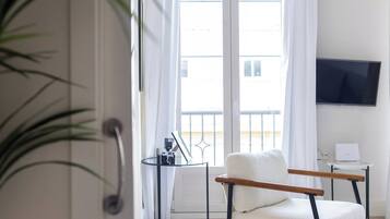 Un salón moderno con sofá, televisor y vistas al balcón.
