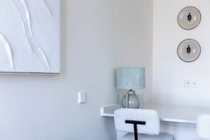 A minimalist room with a white desk, a grey lamp, and two wall-mounted plates with a black design. - The First Suite Apartment (Granada)