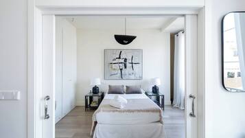 Un dormitorio con cama, mesitas de noche, lámpara, un cuadro y un espejo.