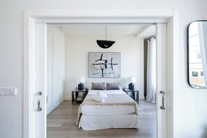 A bedroom with a bed, bedside tables, a lamp, a painting, and a mirror. - The First Suite Apartment (Granada)