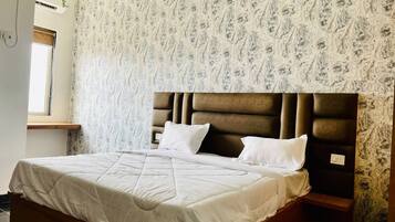 Un dormitorio con una cama grande, cabecera y papel tapiz estampado.