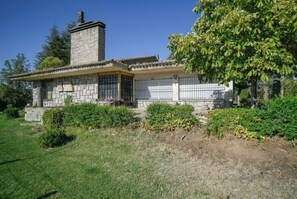 Traditional stone house with a charming porch and beautifully manicured grounds.