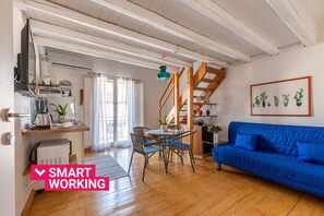 A modern living space with a kitchen, dining area, and a blue sofa. - Sant'Onofrio Mini Loft by Wonderful Italy (Palermo)