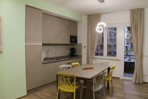 Cocina compacta equipada con microondas, lavamanos y cafetera. Cuenta con una mesa de comedor y cuatro sillas.