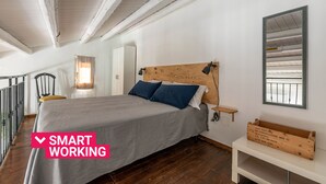 Ein Schlafzimmer mit einem Bett, einem Nachttisch, einem Holzkopfstück, einem Spiegel und einem kleinen Tisch.